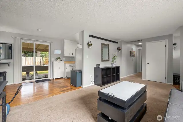 This spacious main living area offers direct access to the home’s private bedrooms and bathrooms, making everyday living feel connected and convenient. Neutral tones and a soft carpeted floor create a comfortable, move-in-ready atmosphere.