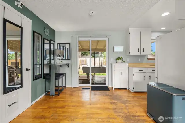 This inviting dining area is filled with natural light from the sliding glass door, offering direct access to the covered back patio—perfect for indoor-outdoor entertaining. The hardwood flooring adds warmth, while the adjacent wall offers space for additional storage or decor.