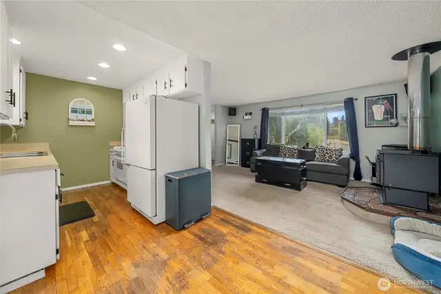 The open layout connects the dining area seamlessly to both the kitchen and living room, creating a functional flow for daily living or gatherings. Recessed lighting and a neutral color palette enhance the bright, welcoming atmosphere throughout the space.