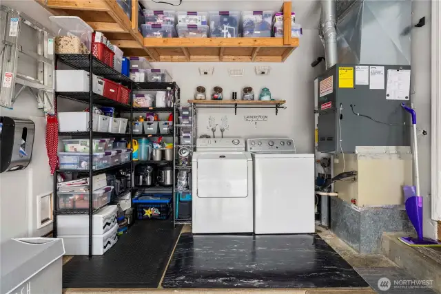 The laundry area is neatly integrated into the garage and includes durable flooring, upper and lower storage space, and easy access to both washer/dryer connections and the home’s HVAC system. Functional and efficient, this space supports multitasking and household management with ease.