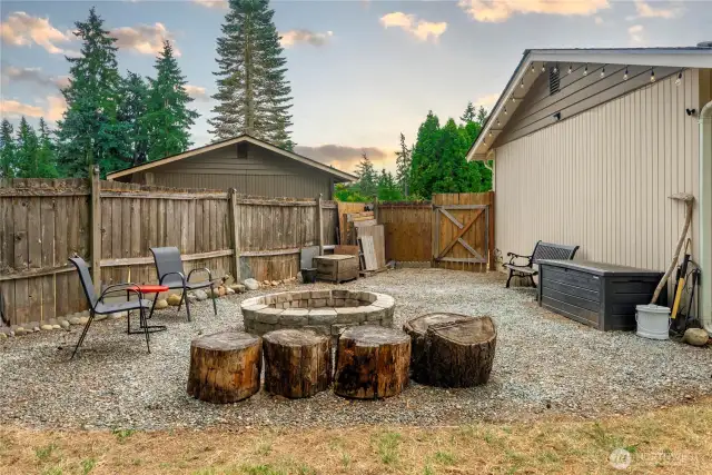 Rustic outdoor fire pit zone featuring natural wood stump seats, patio lighting, and space for storage or additional furnishings.