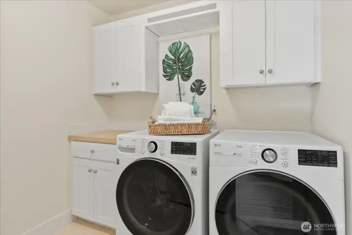 The upstairs laundry room features freshly painted cabinets and is located in a convenient area.