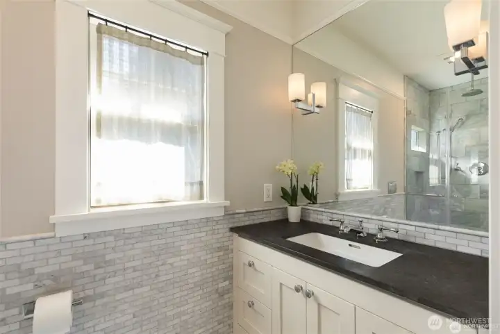 This bathroom was added fairly recently and  features a stone slab vanity, and marble tile  floors and shower
