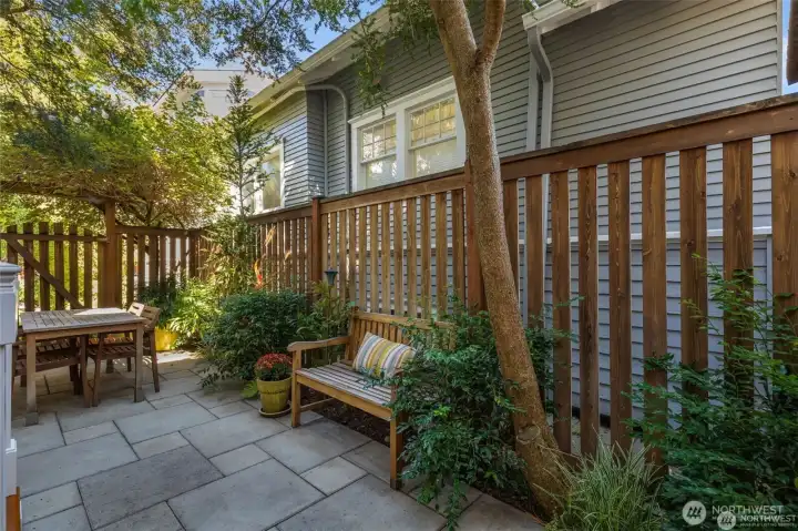 The back yard is so charming! The whole  back area is pavers for usable patio with  space for a dining table and seating. A  fountain fills the air with the soothing sound  of trickling water.