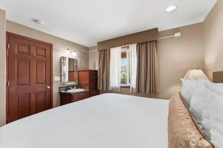 Comfortable primary bedroom suite featuring a convenient built-in dresser and private sink area.