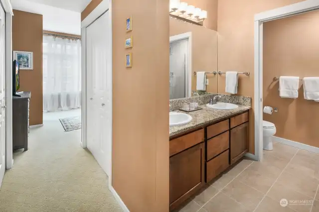 The entry area to the primary suite. Full bath on the right, closets on both sides of the hall and large walk-in closet  with built-ins around the corner