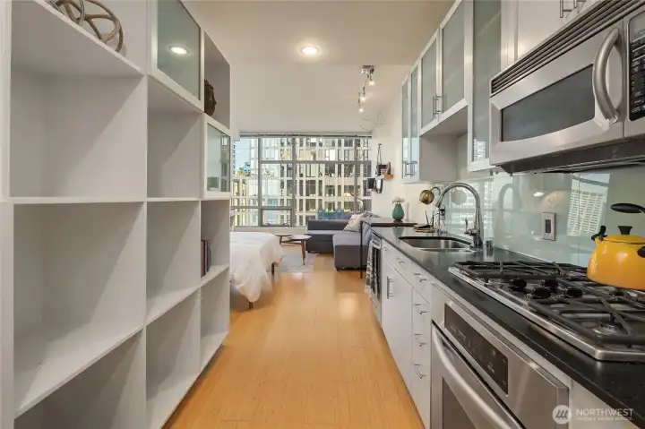 Kitchen offers quality, well-maintained stainless steel aplpiances, easy to clean glass panel backsplash with modern appeal. Black honed quartz counters