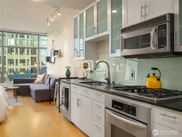 Kitchen offers quality, well-maintained stainless steel aplpiances, easy to clean glass panel backsplash with modern appeal. Black honed quartz counters