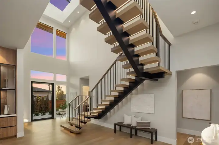 Entryway featuring open mono stringer stairs, a custom 8 panel skylight