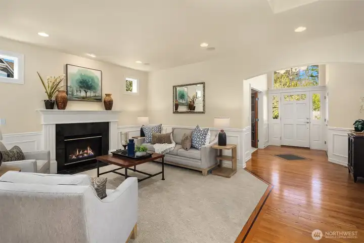 The elegant formal living room impresses with a gas fireplace, soaring ceilings, wainscoting, recessed lighting, and built-in speakers.