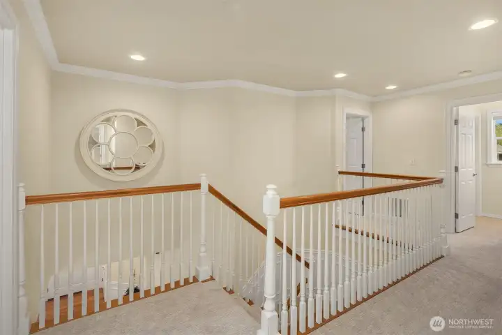 The timeless spindle staircase, framed by continuing wainscoting and crown molding, leads to all four bedrooms and the bonus room.