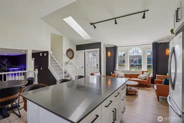 Updated kitchen features quartz countertops, custom cabinetry, stainless steel appliances, tile backsplash, and an oversized island.