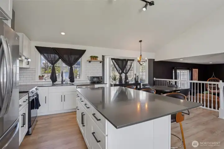 Updated kitchen features quartz countertops, custom cabinetry, stainless steel appliances, tile backsplash, and an oversized island.