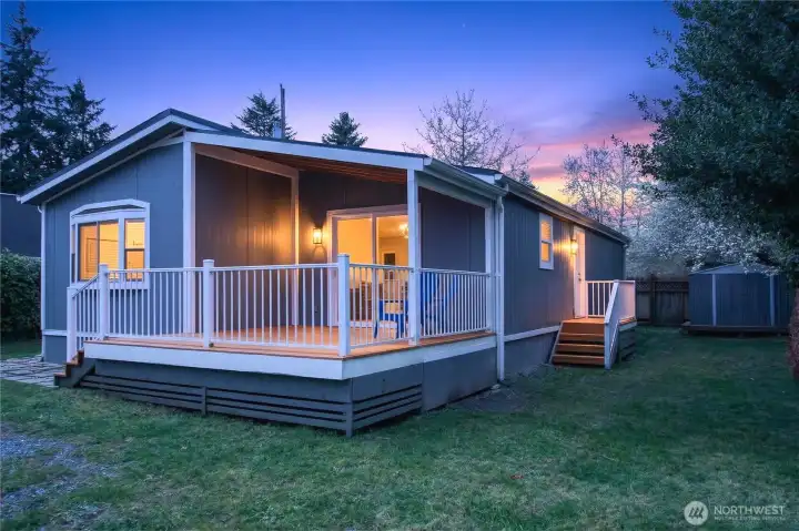 Front Exterior with Large Deck, Covered Porch, Storage Shed, and Twilight Sky