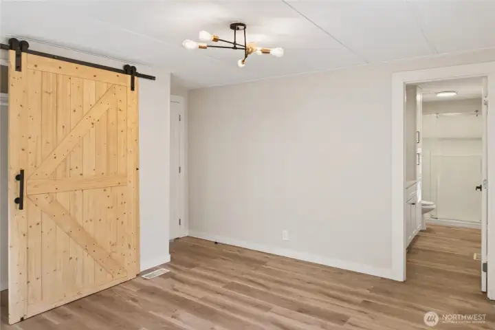 Primary Bedroom with Sliding Barn Door, Sputnik Light Fixture, and En-Suite Bathroom