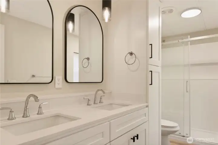 Primary Bathroom with Double Vanity, Quartz Countertops, Arched Mirrors, and Walk-In Shower