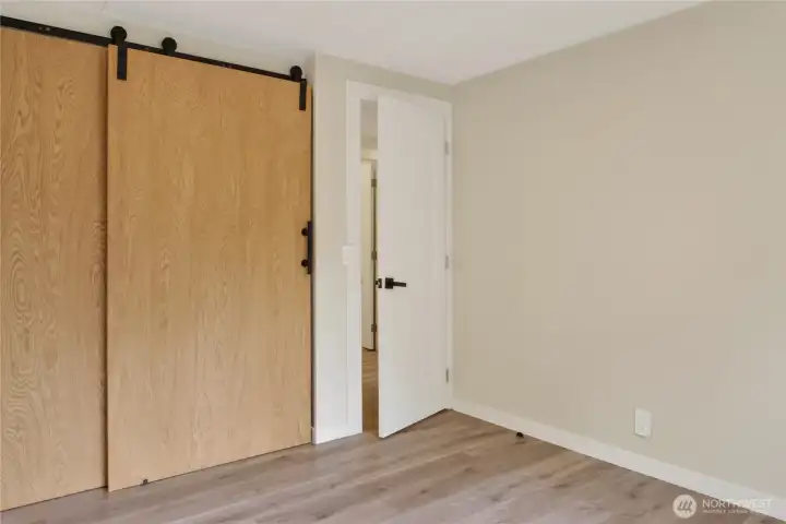 Third Bedroom with Sliding Barn Door Closet and Hardwood-Style Flooring
