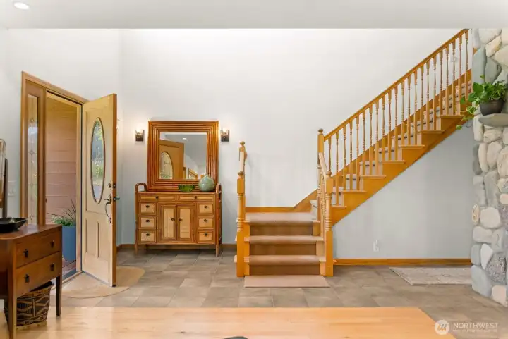 Welcoming front door opens to classic foyer with ceramic tile floors. Stone and rock face of fireplace at entry. Impressive greeting!