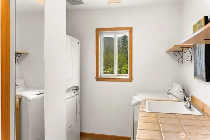 Utility Laundry room on main level of the home. Spacious. Tiled folding counter. Lots of storage. Washer/ Dryer.