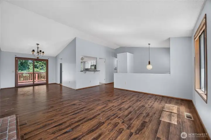 View of Upper level living room with vaulted ceiling, dining room and sliding glass door to deck