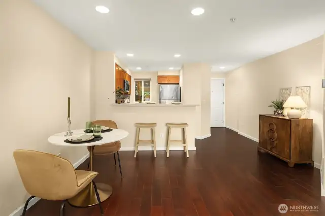 This view shows dining area, kitchen with bar stools, and hallway to entrance. There is a large storage closet next to the door which contains the brand new water heater.