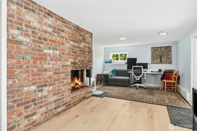 Downstairs living space with brick fireplace, new flooring, doors to the covered patio.
