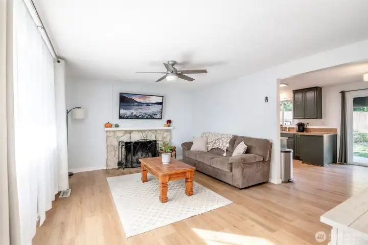 Living room with new LVP flooring and a wood burning fireplace.