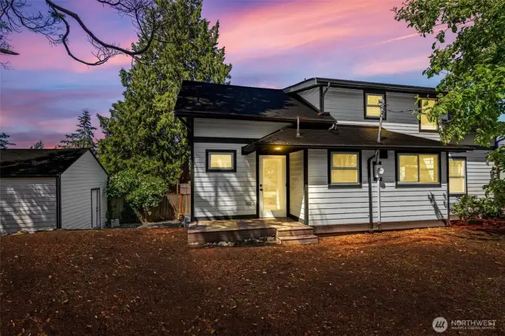 Twilight view of the back and side of the exterior, partially fenced.