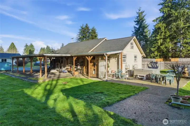 Backside of home with sauna under roof, hot tub.