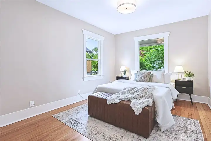 This bright and airy bedroom features beautifully refurbished original hardwood floors and a fresh, neutral color palette, offering a serene and welcoming escape. The classic Craftsman-style trim, modern lighting, and spacious windows allow for an abundance of natural light while maintaining the home's charming 1920s character. This bright and airy bedroom features beautifully refurbished original hardwood floors and a fresh, neutral color palette, offering a serene and welcoming escape. The classic Craftsman-style trim, modern lighting, and spacious windows allow for an abundance of natural light while maintaining the home's charming 1920s character.
