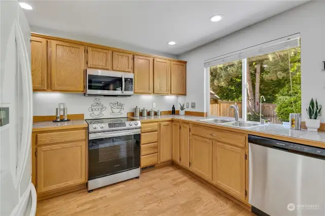Marble tile countertops and all appliances stay in the well-appointed kitchen that includes a newer range/microwave and dishwasher.