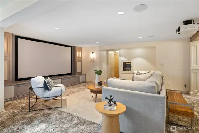 Theater room with 120" movie screen framed with beautiful woodworking and lighting.