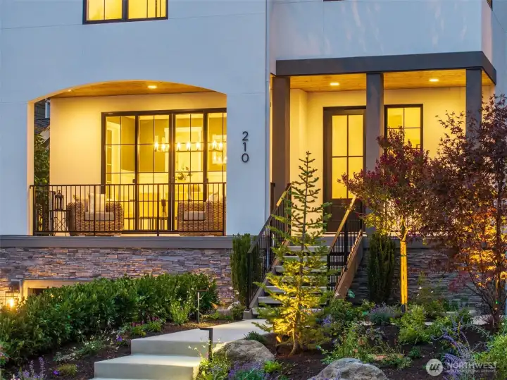 Welcoming front porch with modern lighting, stone accents, and professional landscaping. A picture-perfect entry at twilight.