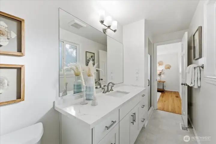 The primary bathroom has been refreshed with a new, timeless vanity featuring a quartz countertop, complemented by fresh paint.