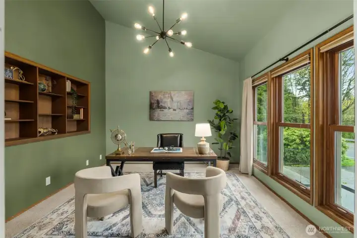 Office with built in shelving and memorable chandelier. An abundance of windows allow natural light to pour in.