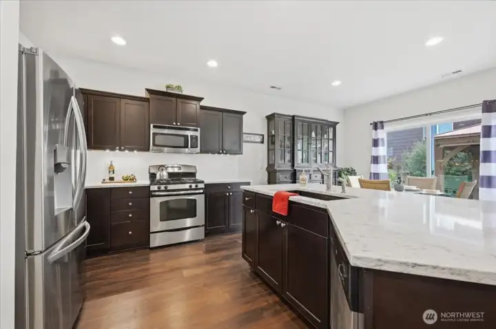 Kitchen has newer quartz counters, stainless appliances, and pantry