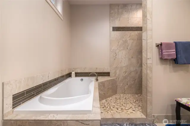 Primary bath has stone tile, a soaking tub, and heated floors for a spa like experience.