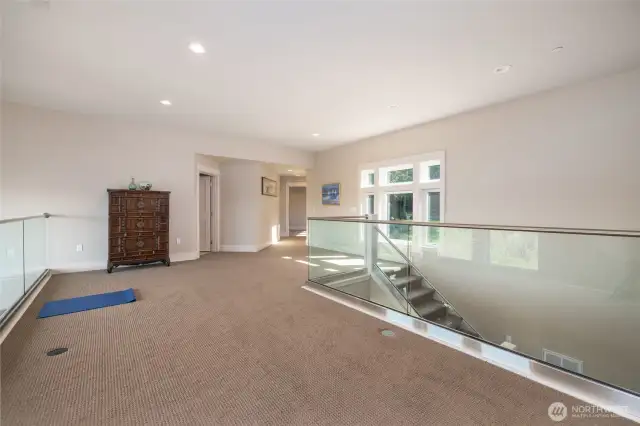 Another view of the bonus room looking towards the stairs and the hallway to a bedroom and the office.
