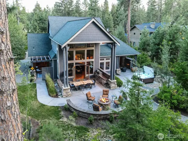 Soaring two-story windows and stunning roof lines emphasize the home's impressive architecture and indoor-outdoor connection. This angle highlights double French doors, covered dining, and the perfect flow from kitchen to firepit.
