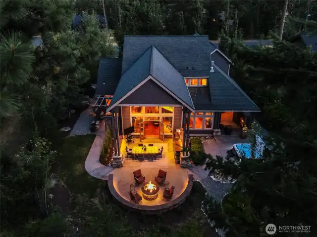 As dusk settles over Suncadia, the home glows warmly from within, inviting you to gather around the firepit or enjoy the tranquility of the forest. This view captures the ambiance and retreat-like quality of the backyard at night.