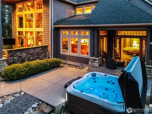 A close-up twilight view of the Jacuzzi-brand hot tub, just steps from the primary suite patio. Surrounded by evergreens and under open sky, this private oasis adds spa-grade luxury to everyday living.