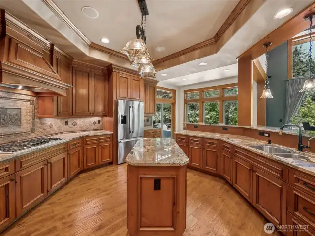 Designed to inspire any home cook — this luxurious kitchen features Bosch double ovens, a gas cooktop with custom wood hood, granite countertops, and a central island. Ample storage, warm wood cabinetry, and views into the great room and yard make this both functional and inviting.