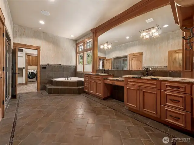 Retreat to comfort in this oversized primary bath with dual vanities, private soaking tub, walk-in shower, and floor-to-ceiling tile. Elegant lighting, built-in linen storage, and direct access to the walk-in closet and laundry area provide a spa-like flow.