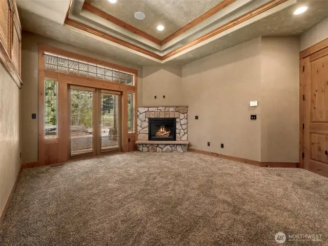 The spacious primary suite offers a cozy gas fireplace, tray ceiling detail, and private patio access leading to the covered hot tub and outdoor fireplace area — creating the ultimate private retreat for morning coffee or evening relaxation.