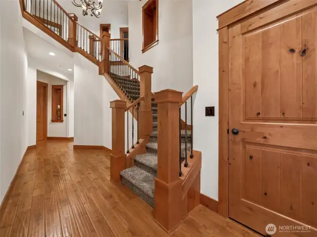 Welcome guests in style with this light-filled foyer boasting warm wood tones, custom iron railings, and an elegant split staircase. Architectural alcoves and chandelier lighting add timeless sophistication.