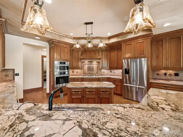 Enjoy a panoramic view of the chef’s kitchen from the raised breakfast bar. Rich granite countertops, pendant lighting, and double ovens complement the space designed for entertaining and effortless cooking.