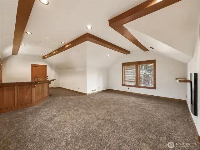 Spacious and open, this upstairs bonus room features vaulted ceilings with beam accents, plush carpet, and room for a home theater, game table, or secondary living space. Connected to the wet bar for easy entertaining.