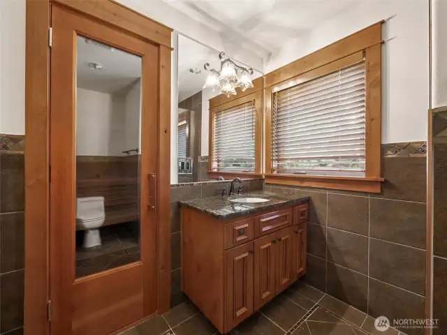 Your private wellness retreat includes a Finlandia dry sauna behind a glass door, paired with a beautifully tiled bathroom complete with granite vanity and ambient lighting — perfect for post-golf relaxation or cold therapy.