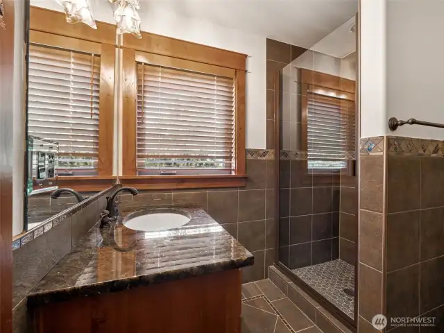 Thoughtfully designed guest bath offers a granite countertop, custom tilework, and a step-in glass shower. A calm and refined space for visitors or family, just off the upper level bonus room.