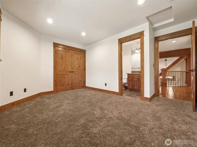 A spacious upstairs bedroom with plush carpet, wood-trimmed doors, and direct access to a full ensuite bath, creating the ideal guest or secondary suite for long stays or multi-generational living.